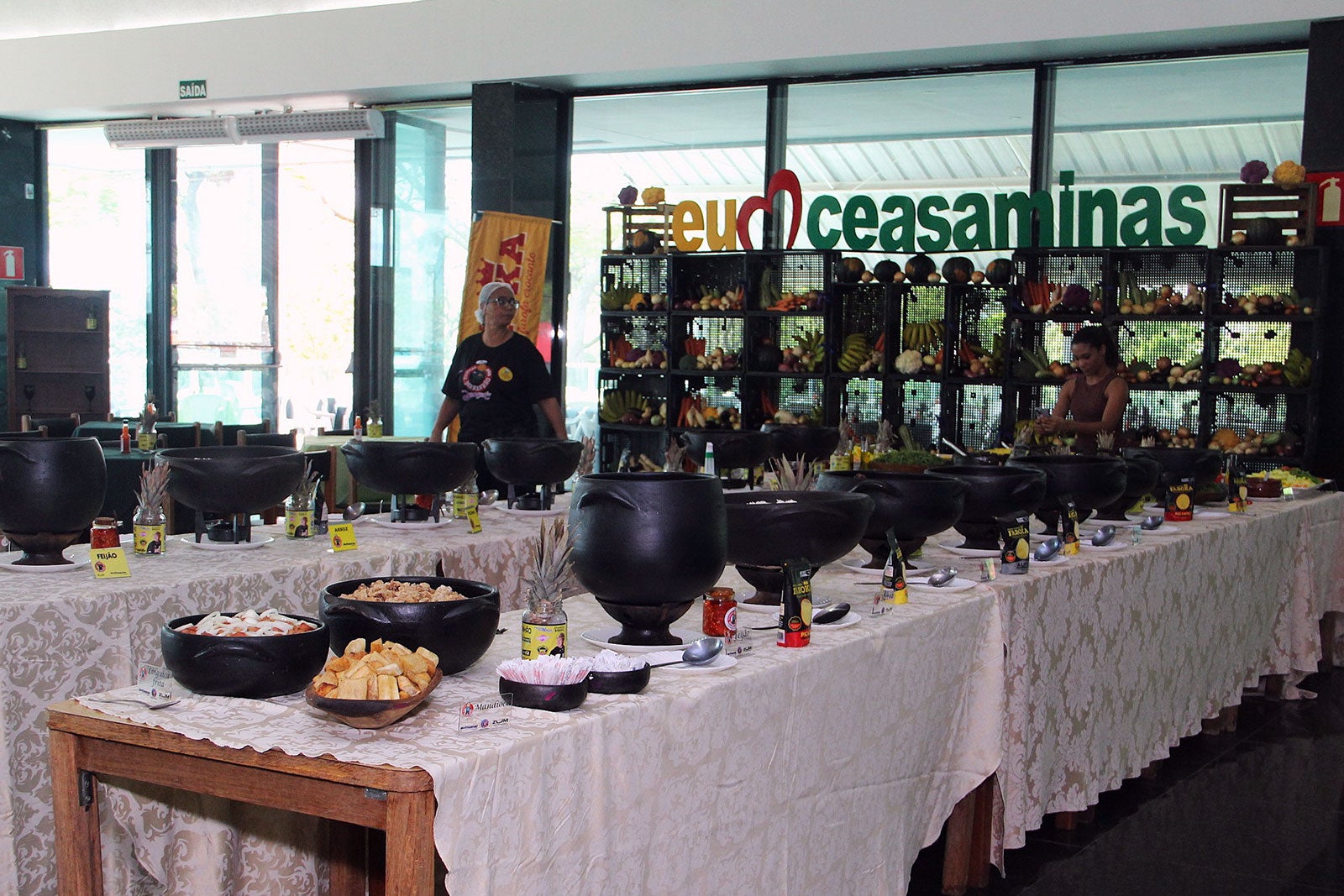 Buffet da Feijoada do Maranhão com panelas e acompanhamentos dispostos sobre mesas