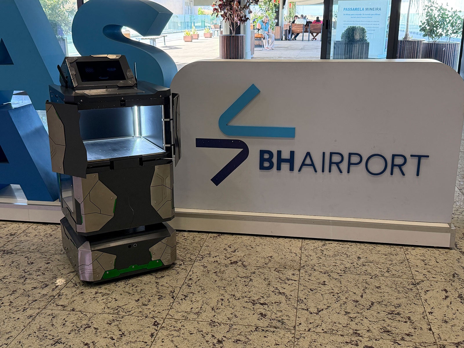 Robô de entregas no BH Airport ao lado da sinalização do terminal